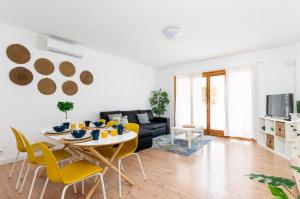 a living room with a table and yellow chairs at Port Apartments in Port d'Alcudia