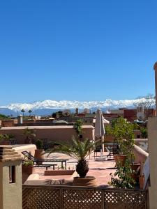 balcón con mesas y sillas y vistas a las montañas en Riad Jnan El Cadi, en Marrakech
