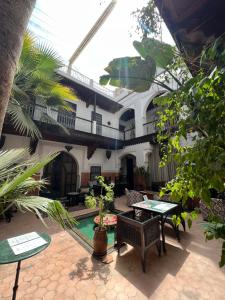 een patio met een tafel en stoelen en een gebouw bij Riad Jnan El Cadi in Marrakesh