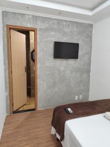 a room with a bed and a flat screen tv on a wall at Residencial 7 Mares in Rio das Ostras