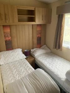 two twin beds in a small room with a window at Keeonah 220 Kestrel Close in Saltfleet