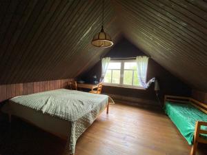 a attic room with a bed and a window at Ethnographic holiday house LAIPAS in Murjāņi