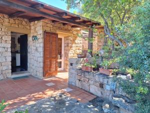a stone house with a wooden door and a brick wall at Villa La Lecceta surrounded by greenery and sea view with sunset in Costa Paradiso