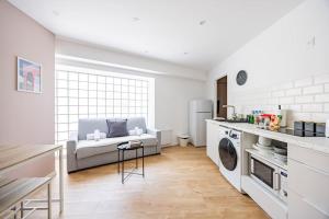 a kitchen and living room with a couch and a table at Charme Parisien 6 Personnes, 2 chambres, 19ème in Paris +6 photos