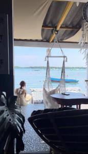 a woman sitting in a room looking out at the ocean at Loyal friend hostel karimunjawa in Karimunjawa