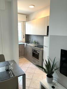 a kitchen with white cabinets and a table with a plant at Apartment Cuore del Lido in Lignano Sabbiadoro +13 photos