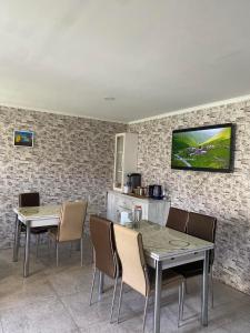 a kitchen with two tables and chairs and a tv on the wall at Old Tower Guesthouse Ushguli in Ushguli