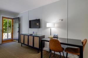 a room with a desk with two chairs and a television at Highbrook Motel in Bar Harbor