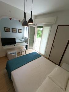Schlafzimmer mit einem großen weißen Bett und einem Schreibtisch in der Unterkunft Hotel Merano in Grado