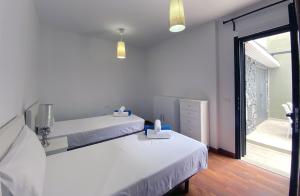 a white bedroom with two beds and a window at Harmony - Beach & Dream rentals in Playa de las Americas +23 photos