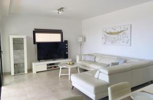 a living room with a white couch and a tv at Harmony - Beach & Dream rentals in Playa de las Americas