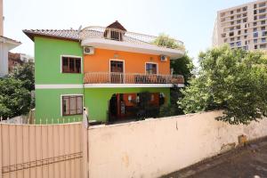 ein grünes und orangefarbenes Haus hinter einem Zaun in der Unterkunft Hostel Osho in Tirana