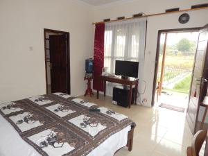 a bedroom with a bed and a desk and a window at Rosella Cottages - Homestay - Yogyakarta in Yogyakarta