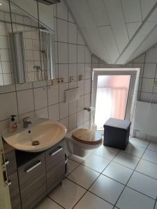 a bathroom with a sink and a toilet and a mirror at Gästehaus Windheim (Büchig) in Stutensee