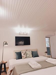 a white bedroom with a bed with a tv on the wall at Casa Myrilla in Corfu