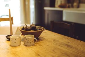 a bowl of pears on a wooden table with two cups at The Old Timber Store in Youlgreave