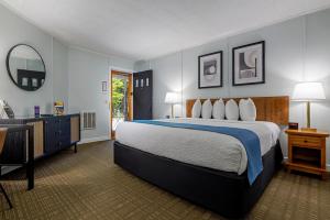 a bedroom with a bed and a desk and a mirror at Highbrook Motel in Bar Harbor