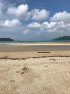 an empty beach with sand and clouds in the sky at 檸檬草ー奄美の自然の香る宿ー in Amami