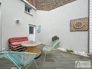 a patio with a table and chairs and a couch at Élégance Malouine - 500m Plage in Dunkerque