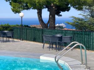 a patio with tables and chairs next to a swimming pool at Les Chênes-lièges d'Ambeille in Collioure
