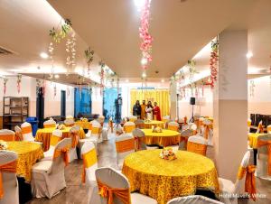 um salão de banquetes com mesas e cadeiras amarelas em Mavens White Artemis Hospital Road Sector 52 Gurgaon em Gurgaon