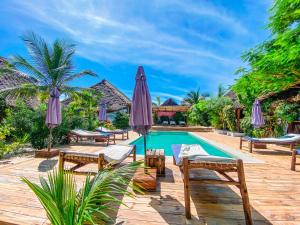 einen Pool in einem Resort mit Stühlen und Sonnenschirmen in der Unterkunft Ananda Beach Hotel in Paje