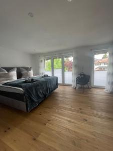 a bedroom with a bed and wooden floors and windows at Haus Gerberstraße - Ferienhäuser Alpenglück in Oberstdorf