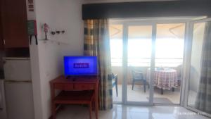 a living room with a tv on a table with a dining room at Casa Jardins da Rocha in Portimão
