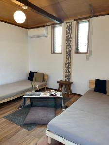 a room with a bed and a table and a couch at 檸檬草ー奄美の自然の香る宿ー in Amami
