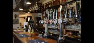 Eine Bar mit einem Haufen Gläser auf der Theke. in der Unterkunft The Chequers in Downham Market