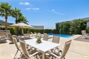 Un patio con una mesa y sillas blancas. en ViVi Homes -Villa Yara Pool, Sauna, Spa & Garden, en Mijas