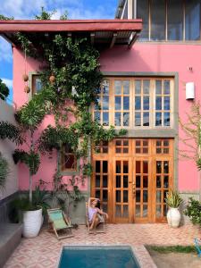 a woman sitting in a chair in front of a pink house at Secret Cottage Granada Nicaragua in Granada