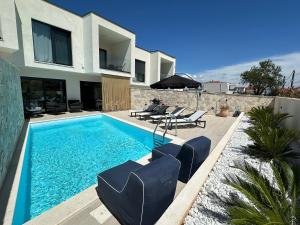a house with a swimming pool with chairs and an umbrella at Lemon Navy house in Vodice