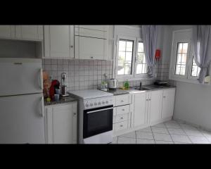 eine Küche mit weißen Schränken und einem weißen Kühlschrank in der Unterkunft Lefkada Blue - Apartments in Lefkada Town
