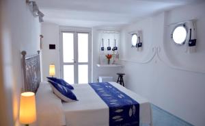 a white bedroom with a bed with blue pillows at Piccolo Hotel Luisa in Ponza