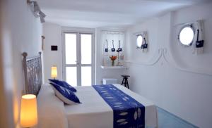 a white bedroom with a large bed with blue pillows at Piccolo Hotel Luisa in Ponza