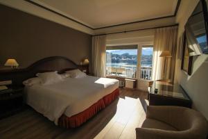 um quarto de hotel com uma cama e uma grande janela em Silken Gran Hotel del Sella em Ribadesella