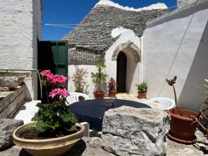 a patio with a table and chairs and flowers at Trulli Cocolicchio in Selva di Fasano