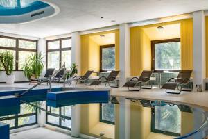 um quarto com uma piscina, cadeiras e janelas em Sporthotel am Semmering em Semmering