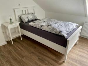 a bed with a black and white comforter and a side table at Haus Jonas in Mechernich