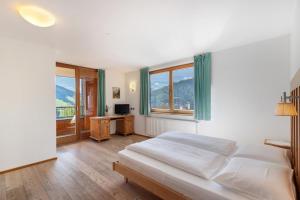 una camera da letto con un letto, una scrivania e finestre di Al Cargá San Vigilio di Marebbe a San Vigilio Di Marebbe