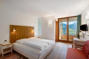 una camera da letto con un letto, una scrivania e una finestra di Al Cargá San Vigilio di Marebbe a San Vigilio Di Marebbe