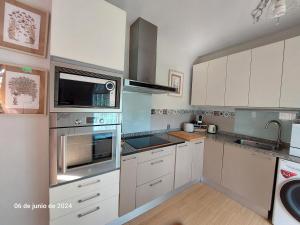 a kitchen with white cabinets and stainless steel appliances at La Casita in Partida de La Cañada