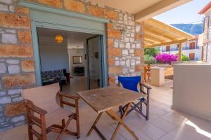 a patio with a table and chairs and a stone wall at Stone House Villa Nanita 2 in Poulithra