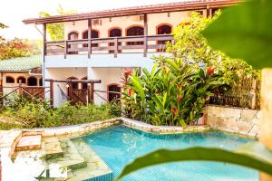 ein Haus mit einem Pool vor einem Gebäude in der Unterkunft VELINN Feiticeira Praia Hotel in Ilhabela