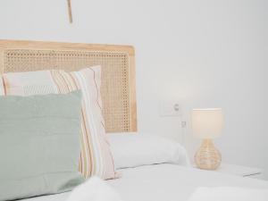 a white bedroom with a bed with pillows and a lamp at Sibs Sanlucar Altamar Nuevo Centrico Tranquilo in Sanlúcar de Barrameda