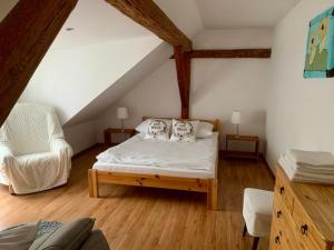 - une chambre mansardée avec un lit et une chaise dans l'établissement Willa Pod Dębem, à Koczarki