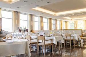 um restaurante com mesas e cadeiras brancas e janelas em Sporthotel am Semmering em Semmering