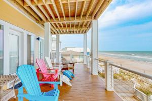 a porch with colorful chairs and a table and the beach at Boundless Horizons in Surf City