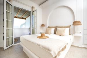 una camera bianca con un letto con un cappello sopra di Thea Suites Naxos ad Agios Prokopios